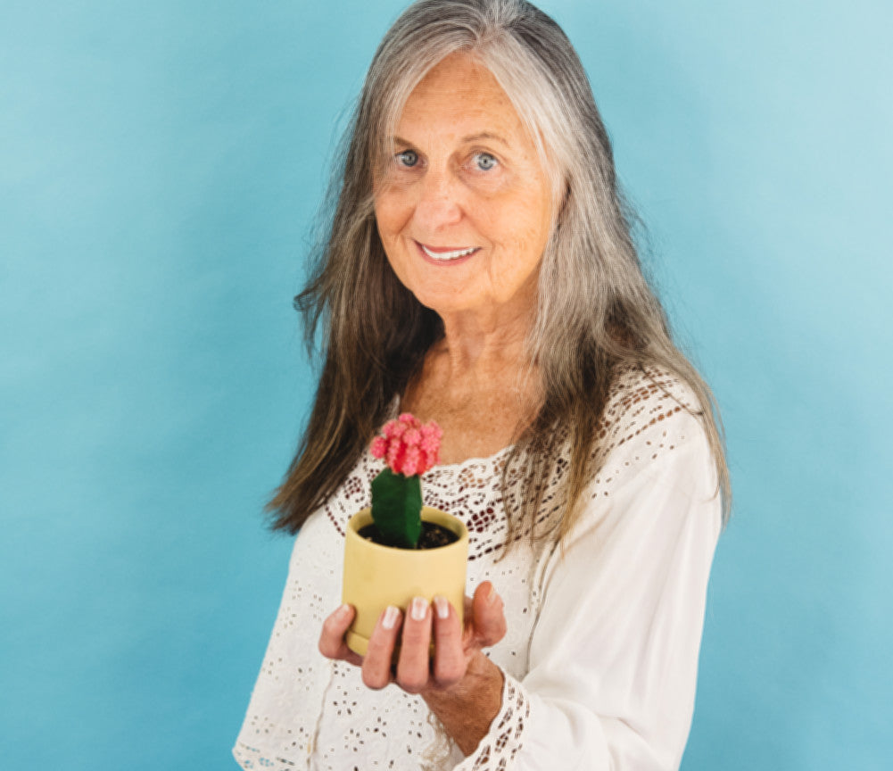 Person holding grafted cactus in yellow ceramic pot.